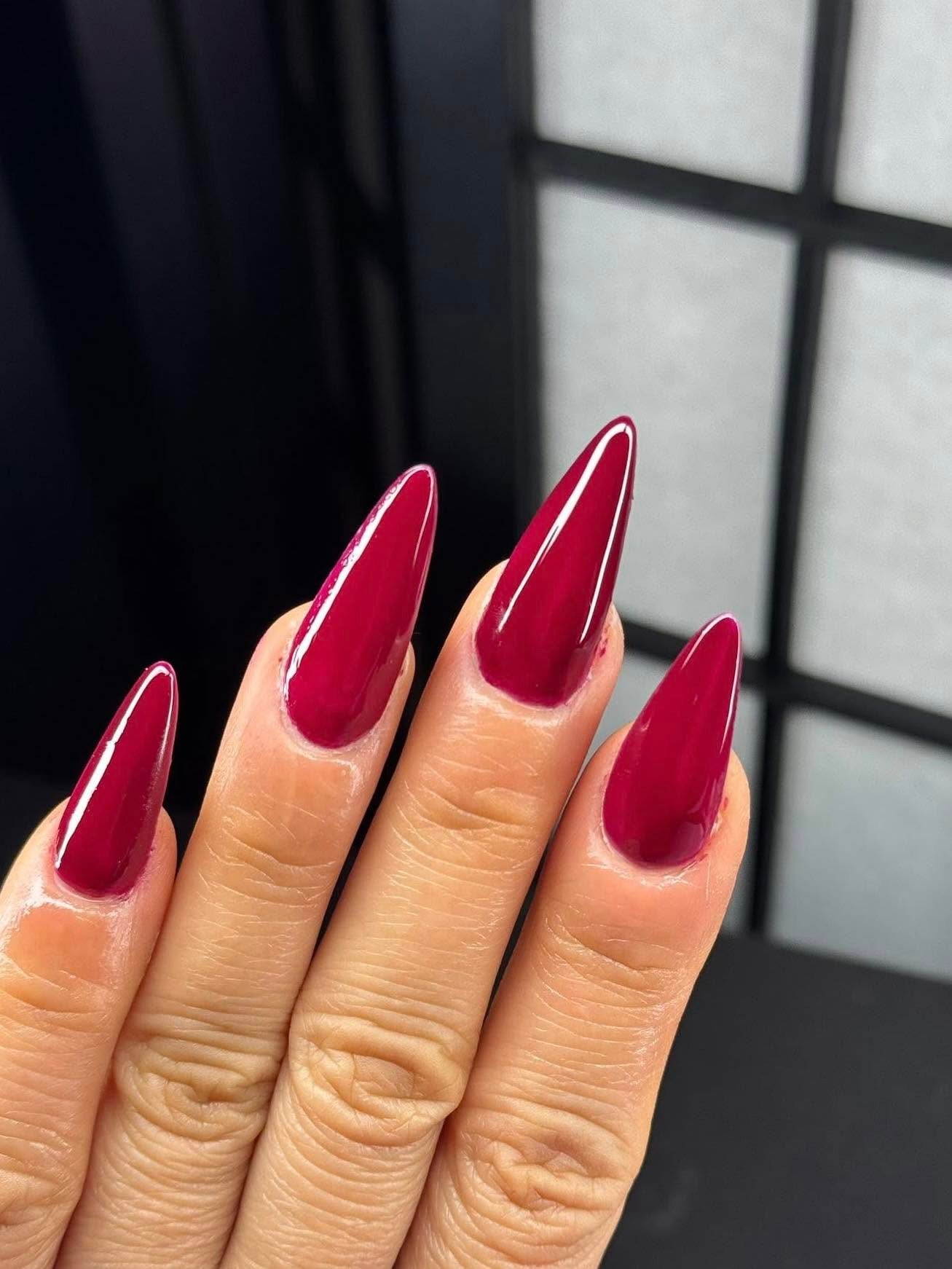 Long stiletto acrylic nails in glossy burgundy
