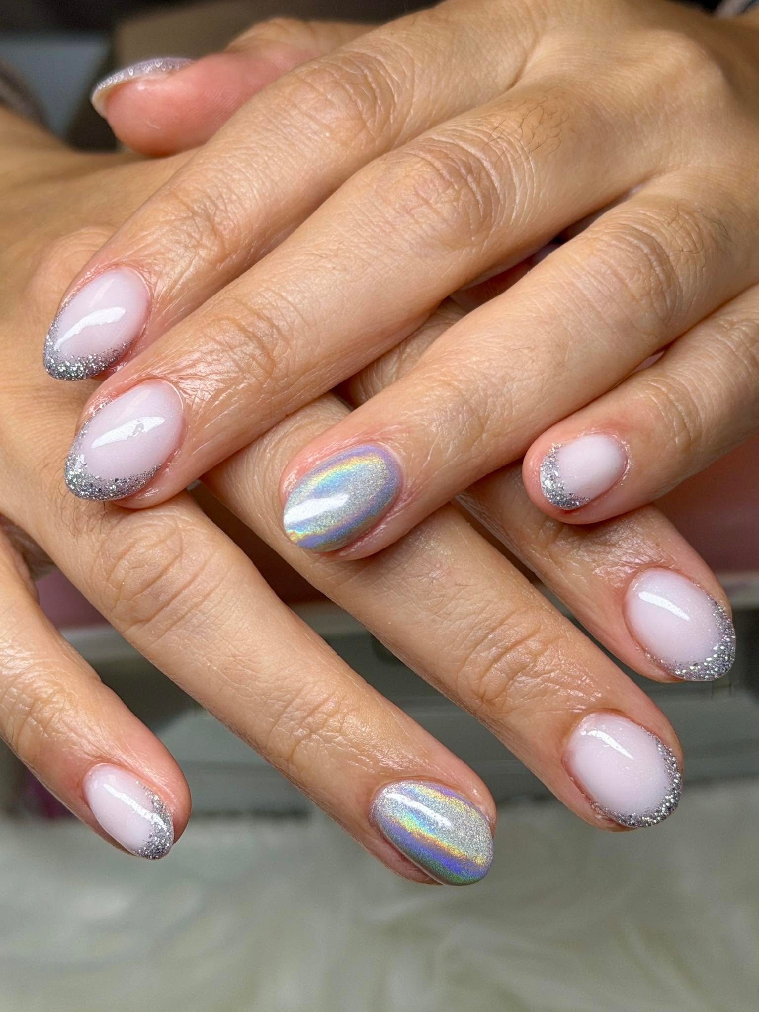 Nude nails with silver glitter tips and a holographic accent