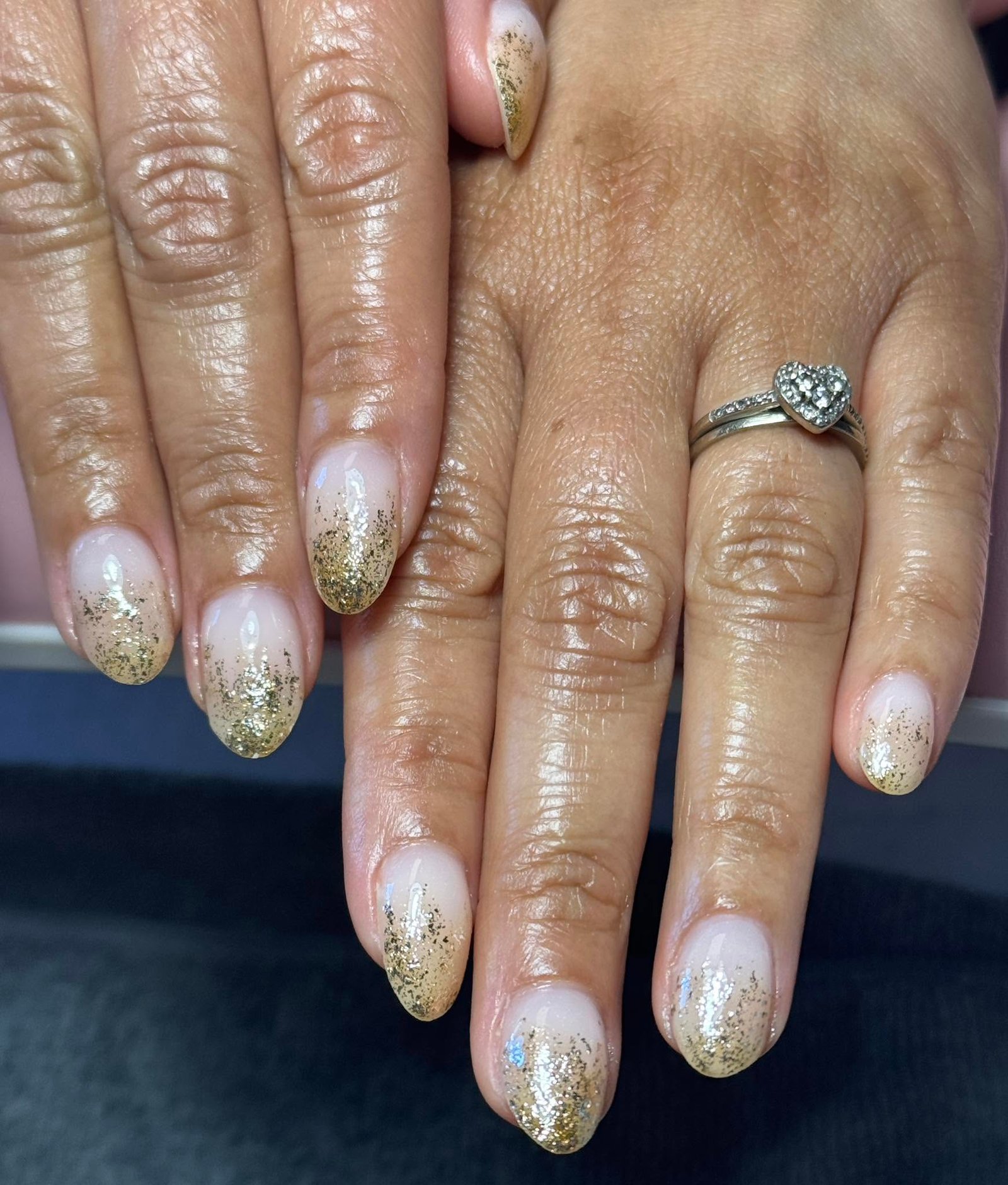 Nude nails with gold glitter ombre tips and a ring