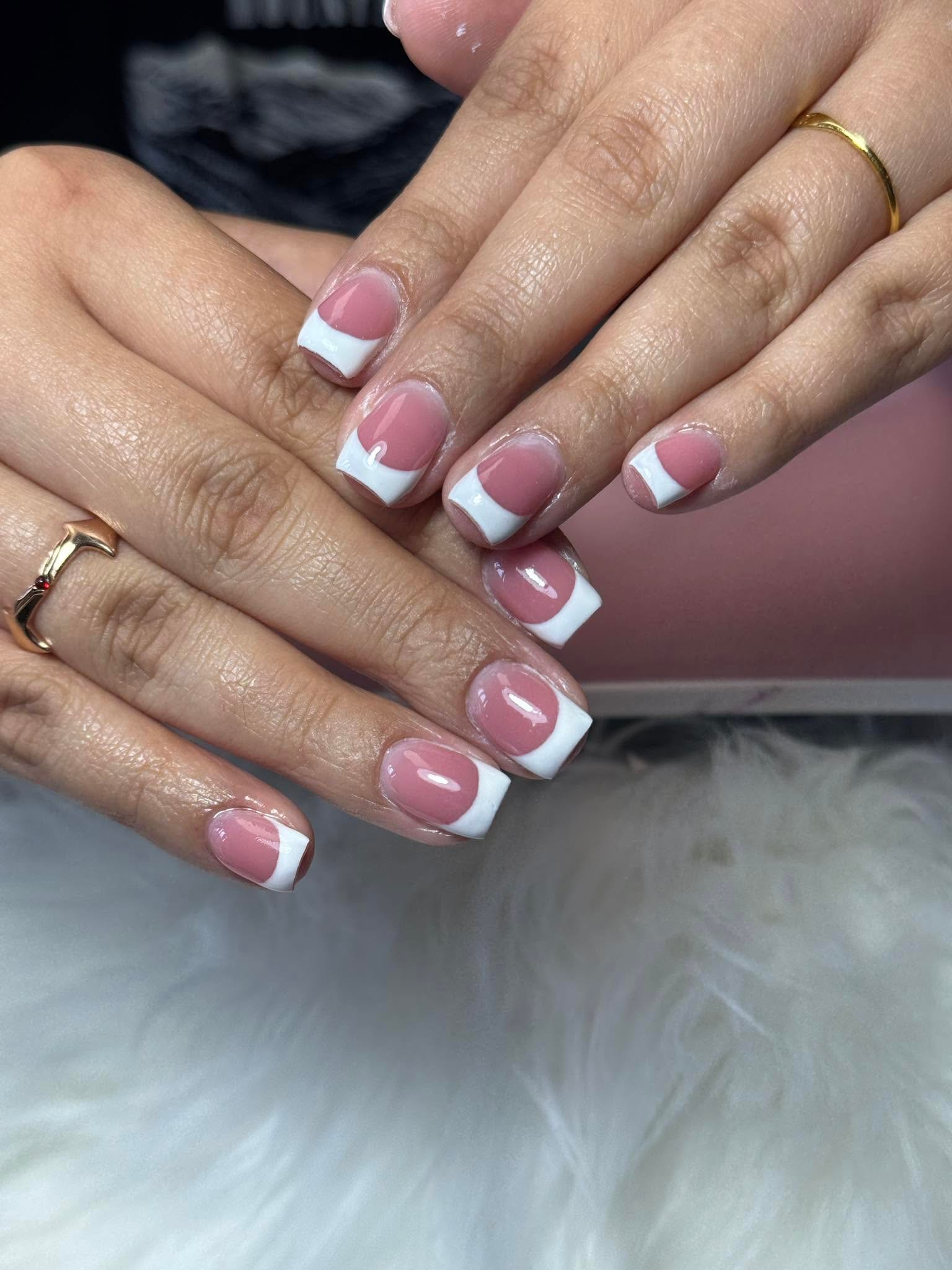 Classic pink and white French manicure with gold rings