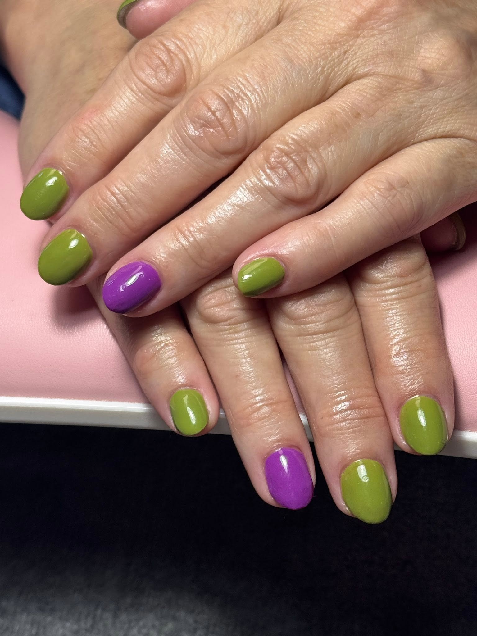 Olive green manicure with a single purple accent nail