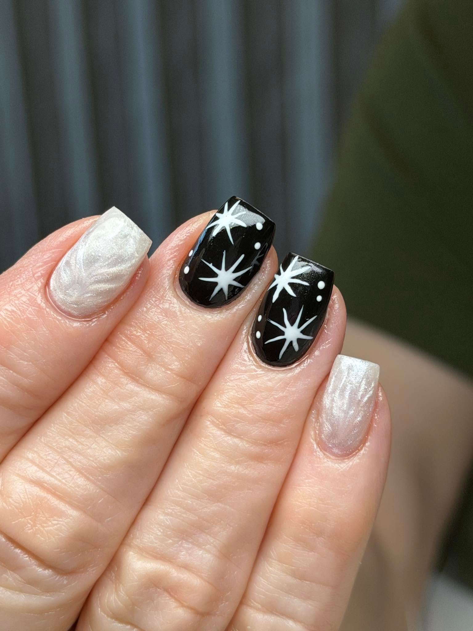 Black and pearl white nails with a starburst design
