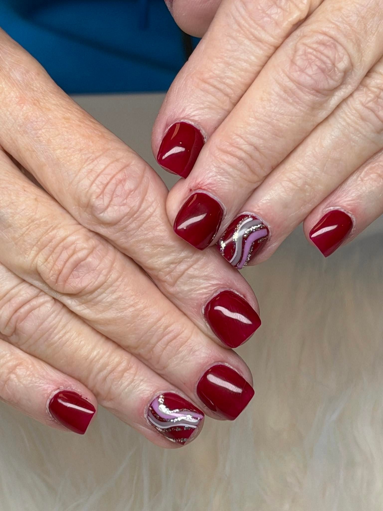 Deep red nails with a glitter swirl accent nail