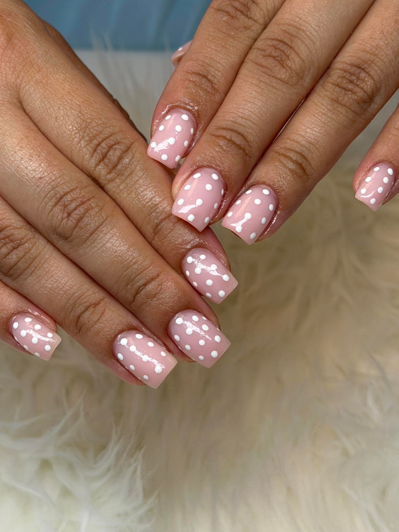 Nude nails with an all-over white polka dot pattern