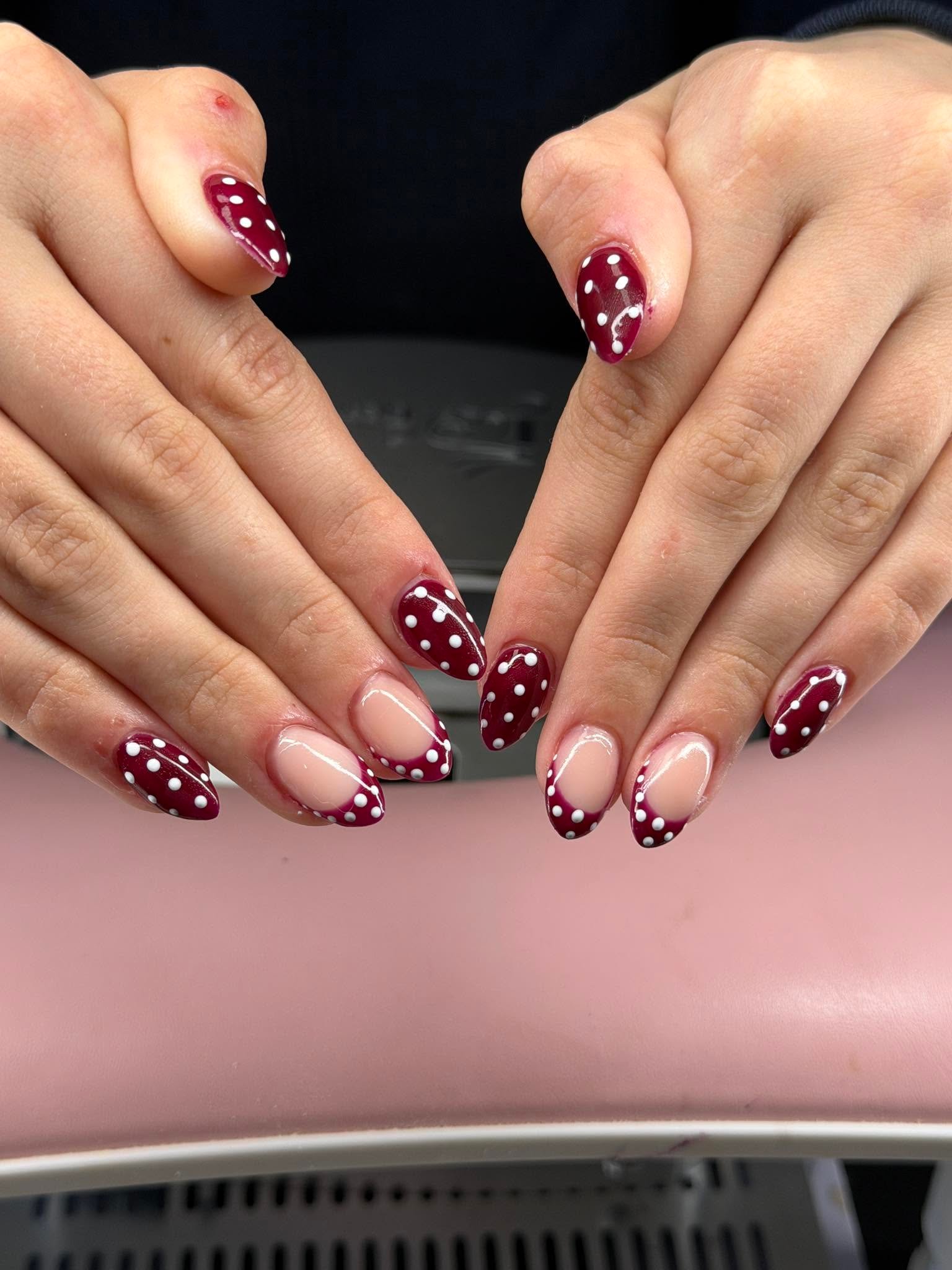Deep maroon nails with white polka dot accents