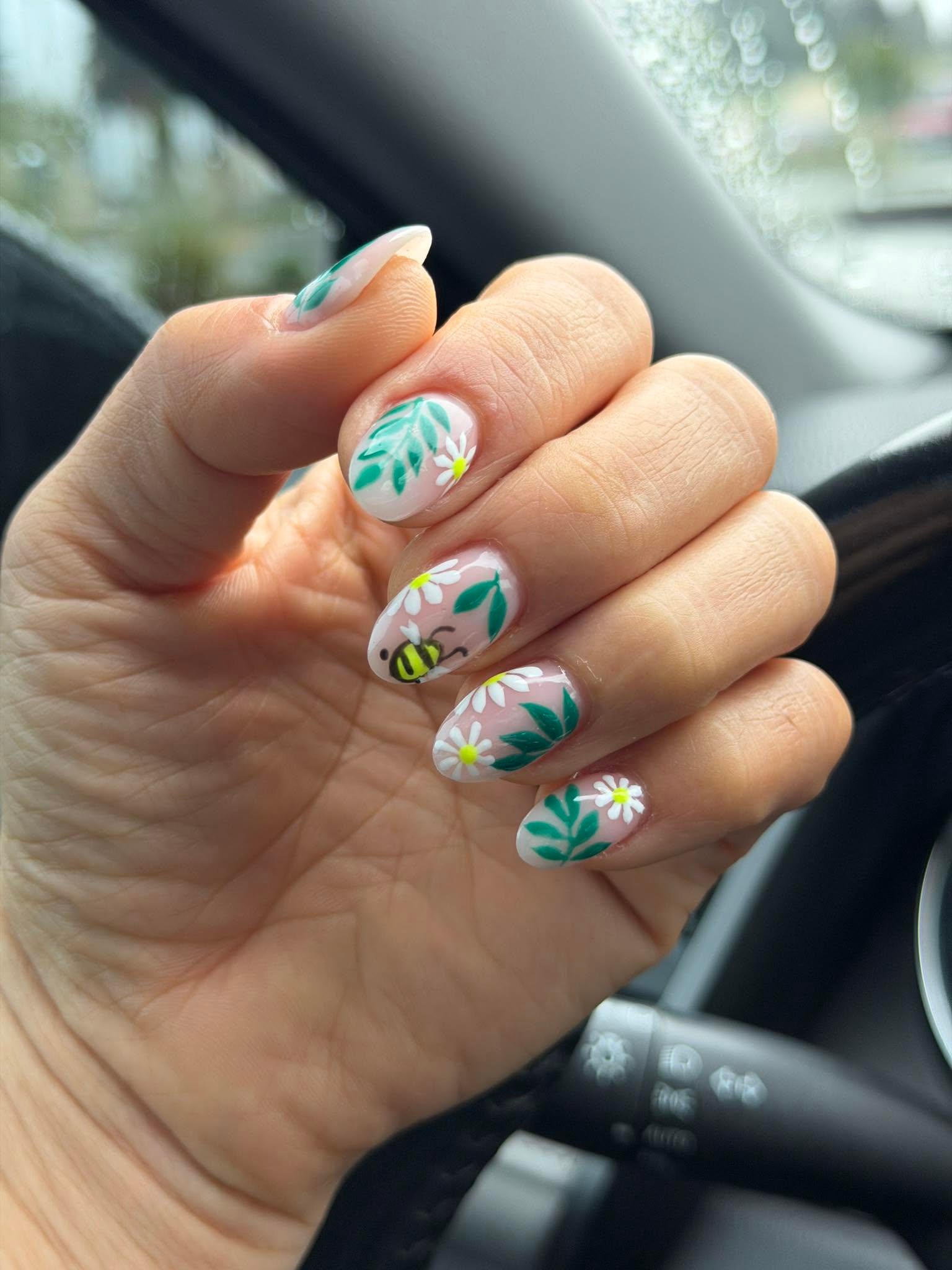 Sheer nails with painted daisies, leaves, and a tiny bee