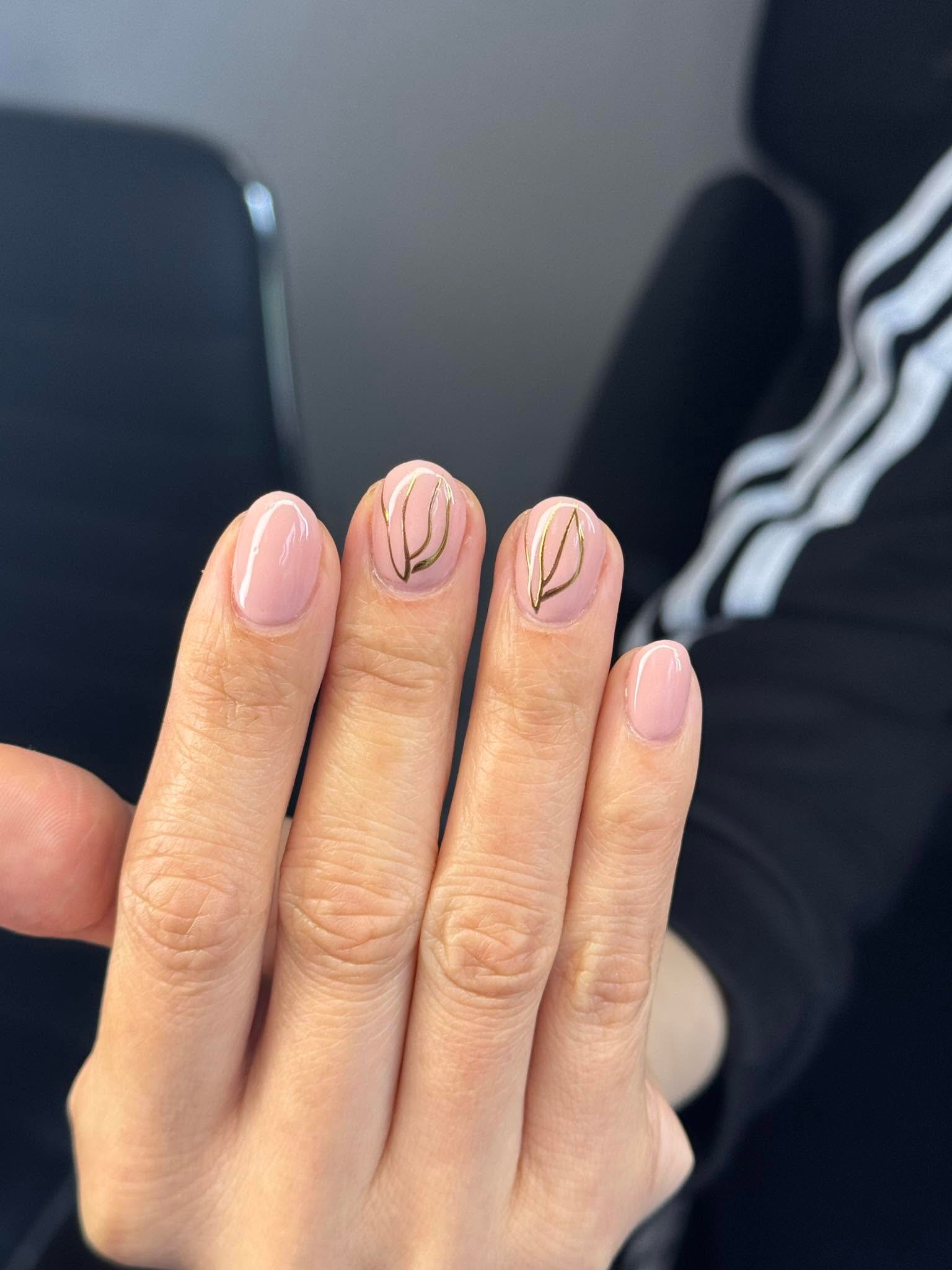 Nude manicure with delicate gold leaf line art accents