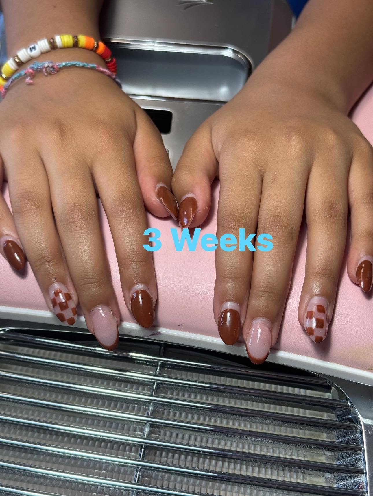 Brown gel manicure with checkered pattern accent nails