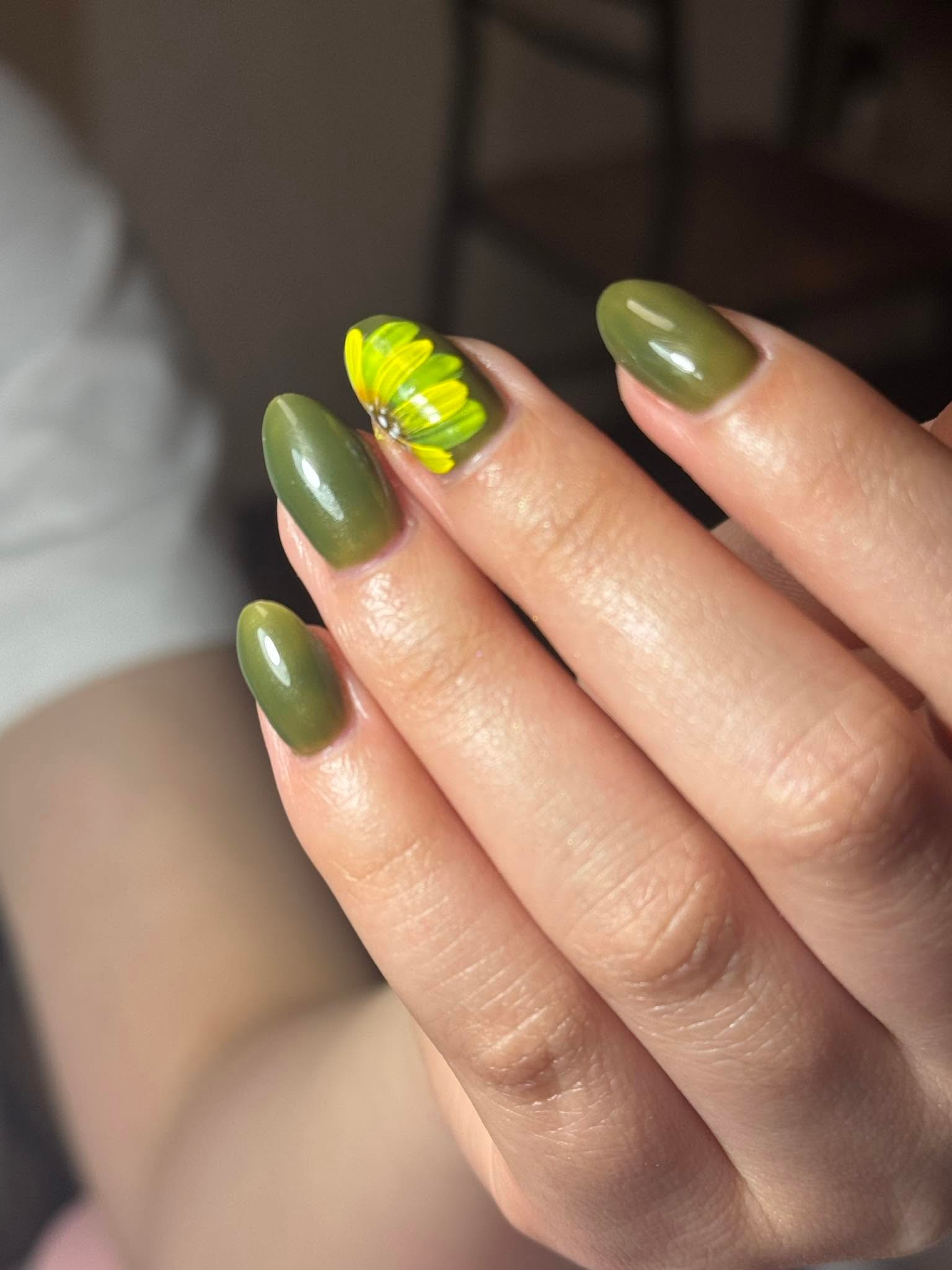 Olive green nails with a hand-painted yellow daisy accent