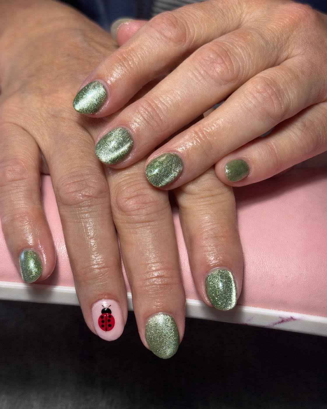 Green glitter nails with a hand-painted ladybug accent