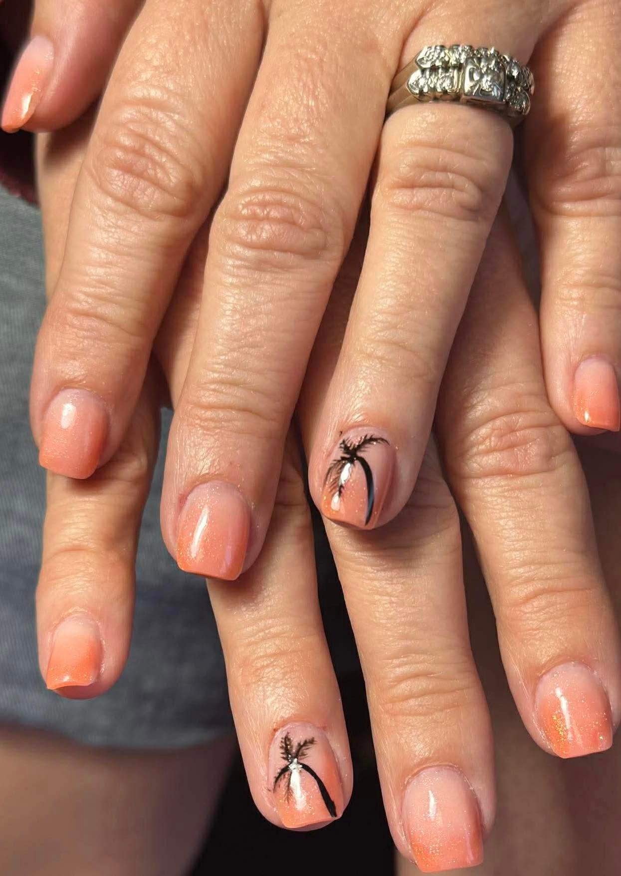 Peach shimmer nails with black palm tree nail art accents