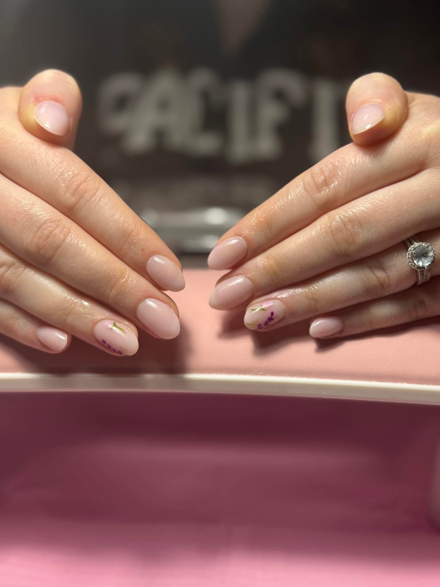 Nude pink nails with small purple floral nail art accents