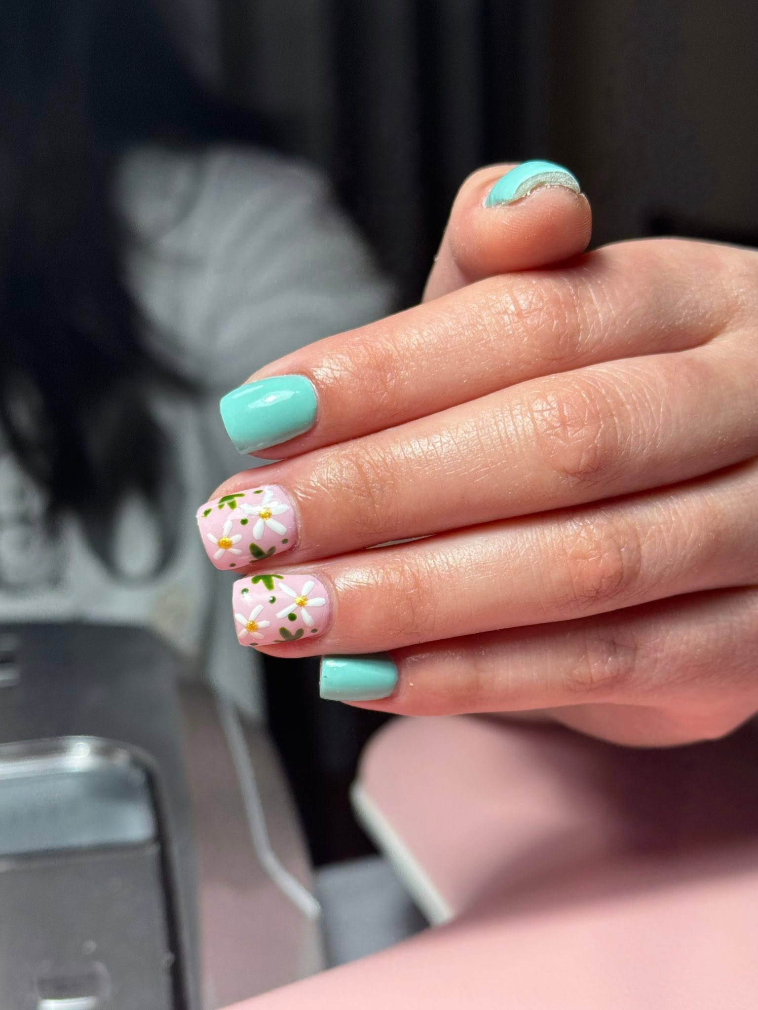 Close-up of mint green and pink daisy nail art