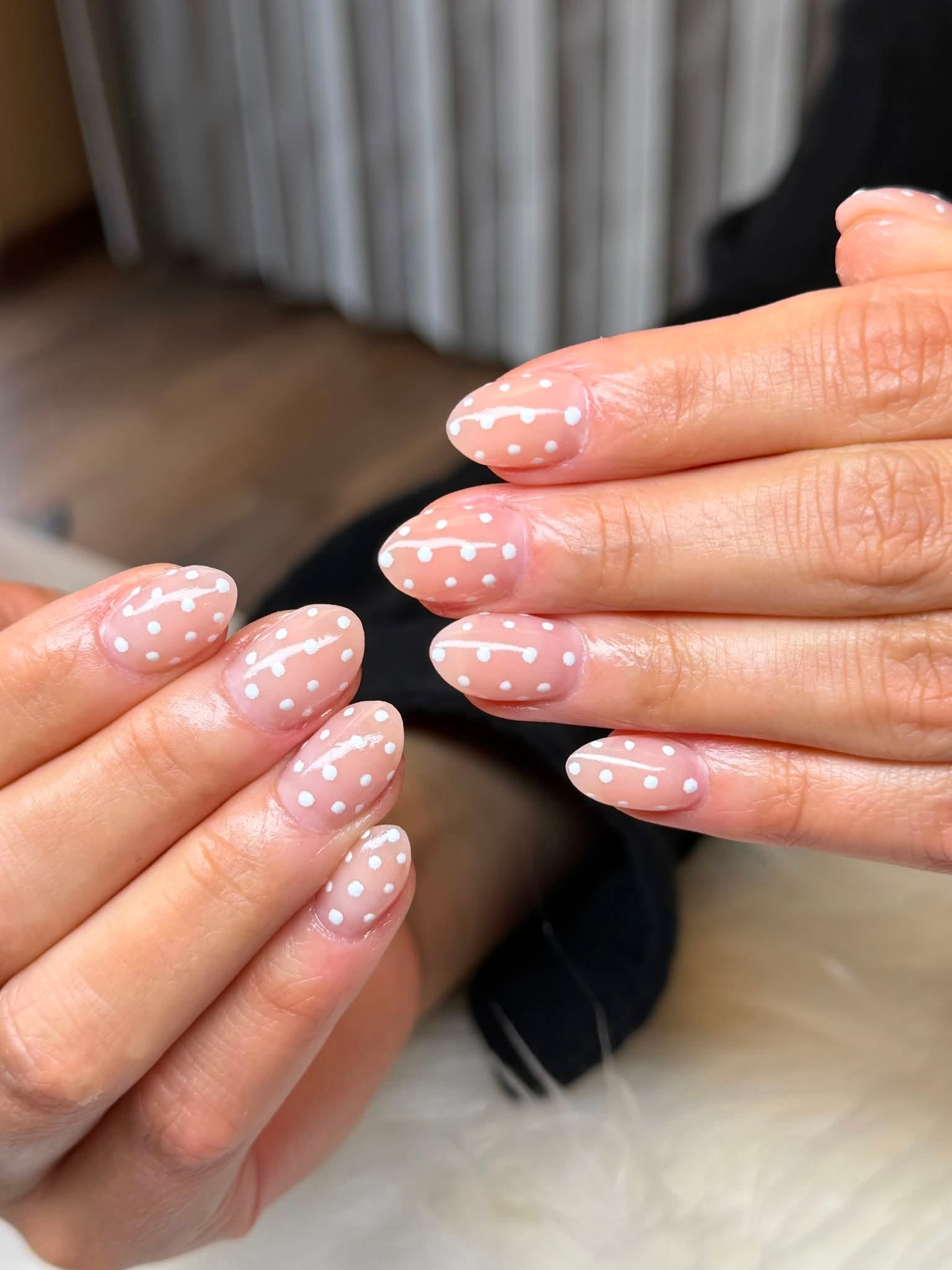Nude nails with a white polka dot pattern