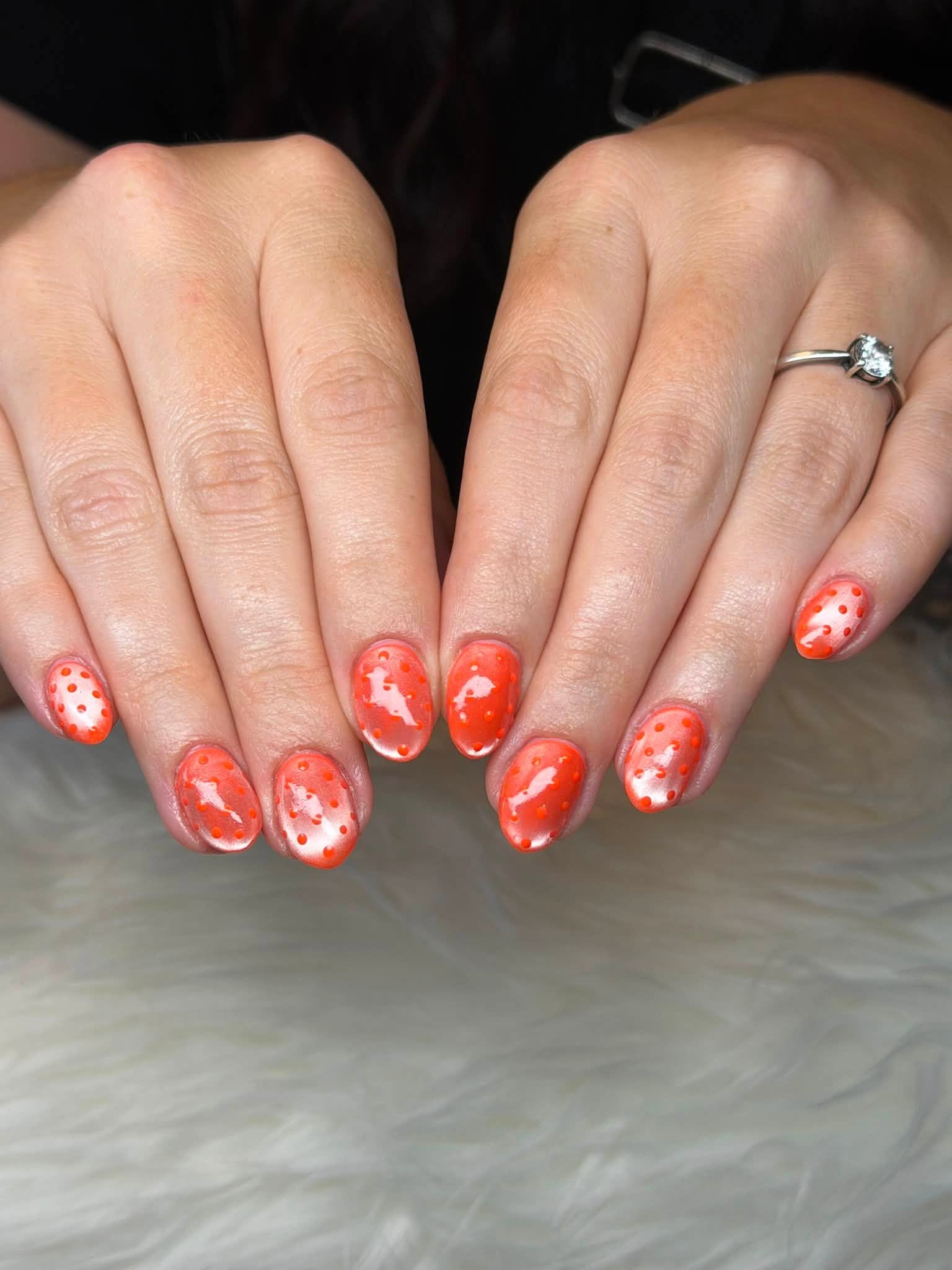 Coral manicure with polka dot pattern
