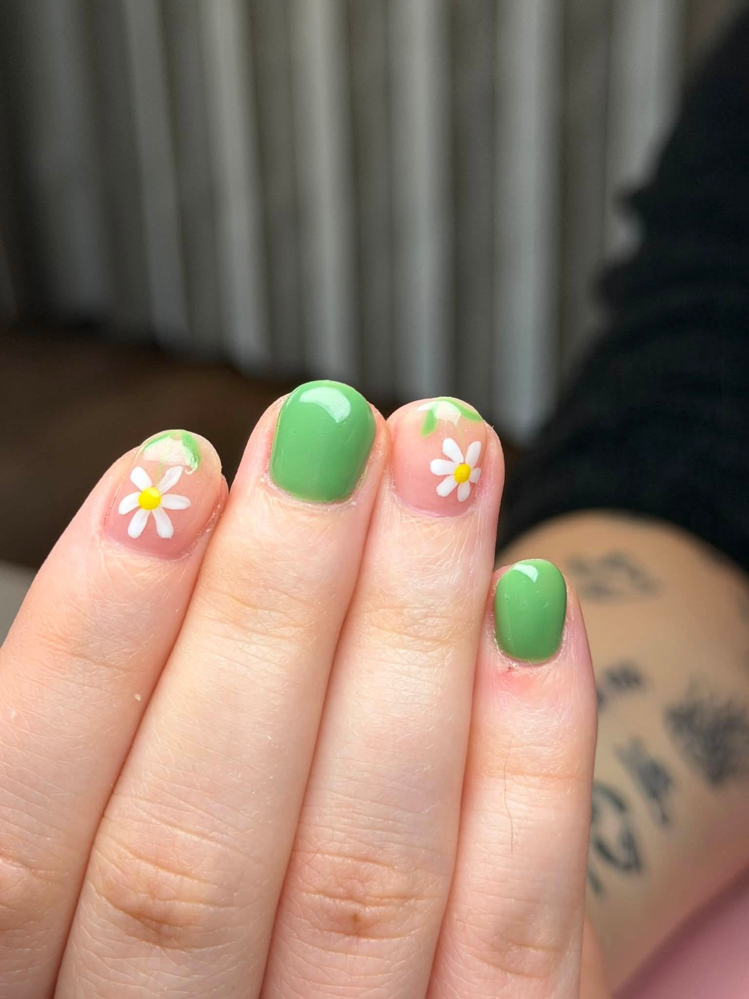 Green manicure with painted daisy flowers
