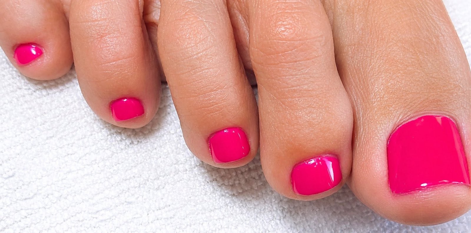 Bright pink glossy pedicure on toes